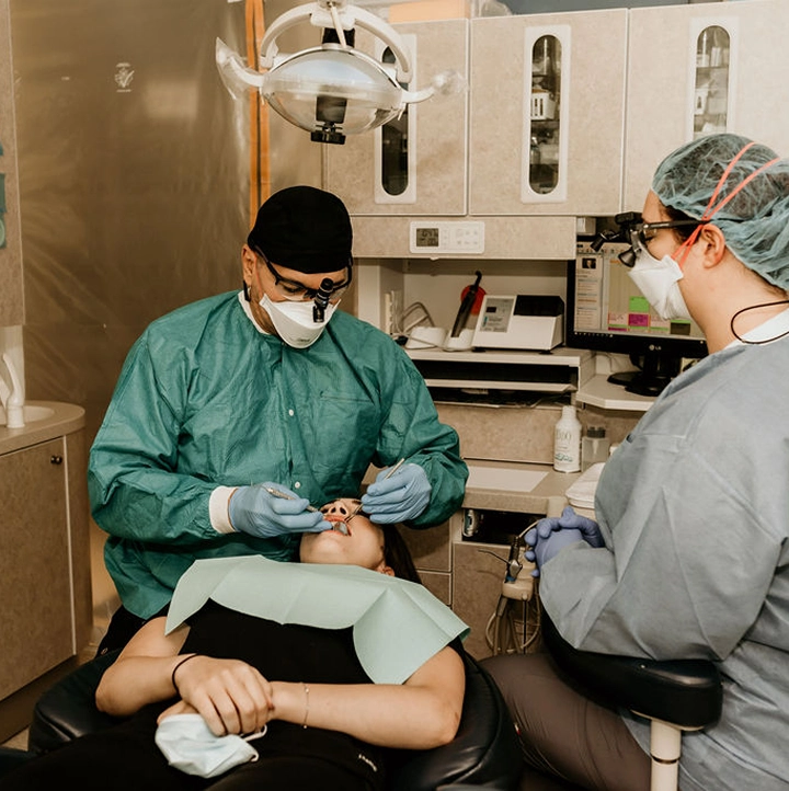 A dentist performing a dental procedure on a patient while a dental assistant observes.